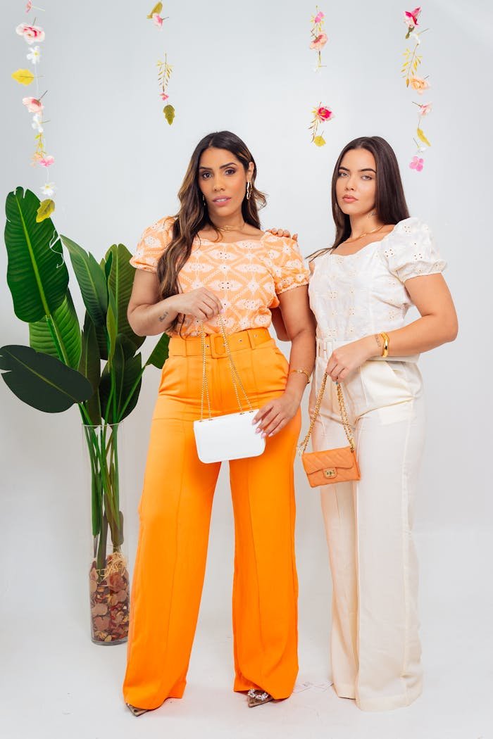 Two fashionable women posing indoors with vibrant outfits and stylish accessories, summer vibes.