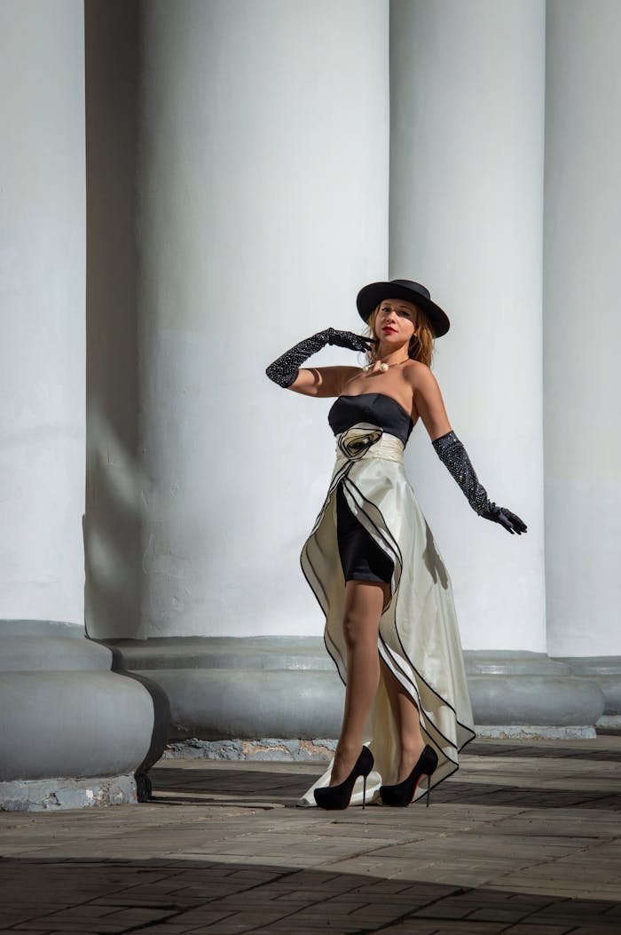 Stylish woman in modern attire posing outdoors by grand columns, exuding elegance and confidence.